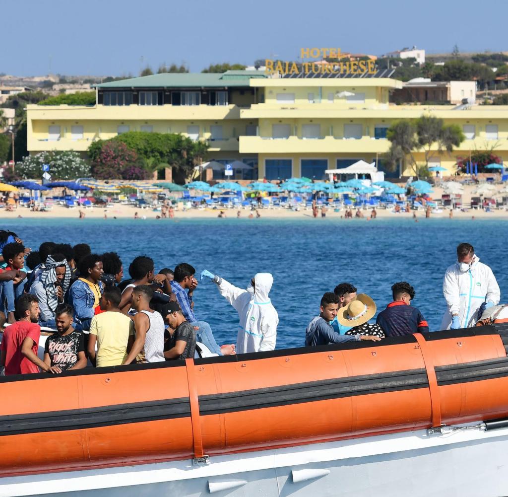 Migranten aus Tunesien und Libyen werden bei ihrer Ankunft in Lampedusa auf Anzeichen einer Koronainfektion untersucht