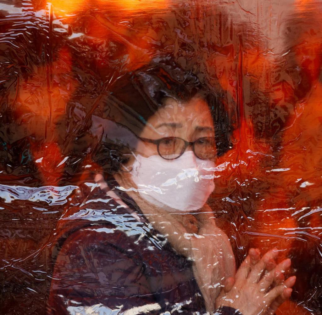 Eine Mutter betet hinter einer Plastikplane in einem buddhistischen Tempel in Seoul für die Gesundheit ihrer Kinder und den Schulerfolg trotz der schwierigen Corona-Zeiten