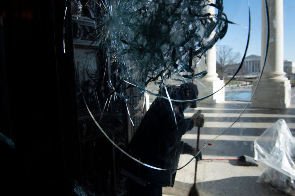 Ein Arbeiter reinigt Glasscherben von einem der Eingänge zum US-Kapitol, nachdem während der Proteste vom Vortag am 7. Januar 2021 in Washington, DC, ein Pro-Trump-Mob in das Gebäude eingebrochen war.  (Foto von Brendan Smialowski / AFP) (Foto von BRENDAN SMIALOWSKI / AFP über Getty Images)
