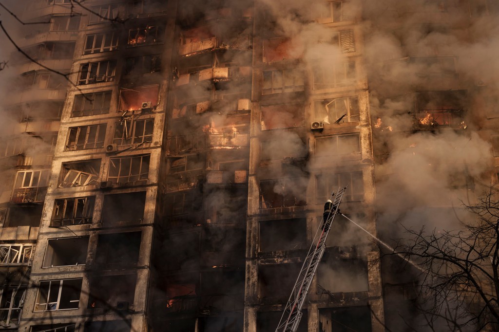 Feuerwehrleute löschen Brände in einem Wohnhaus, nachdem sie in Kiew von Granaten getroffen wurden.