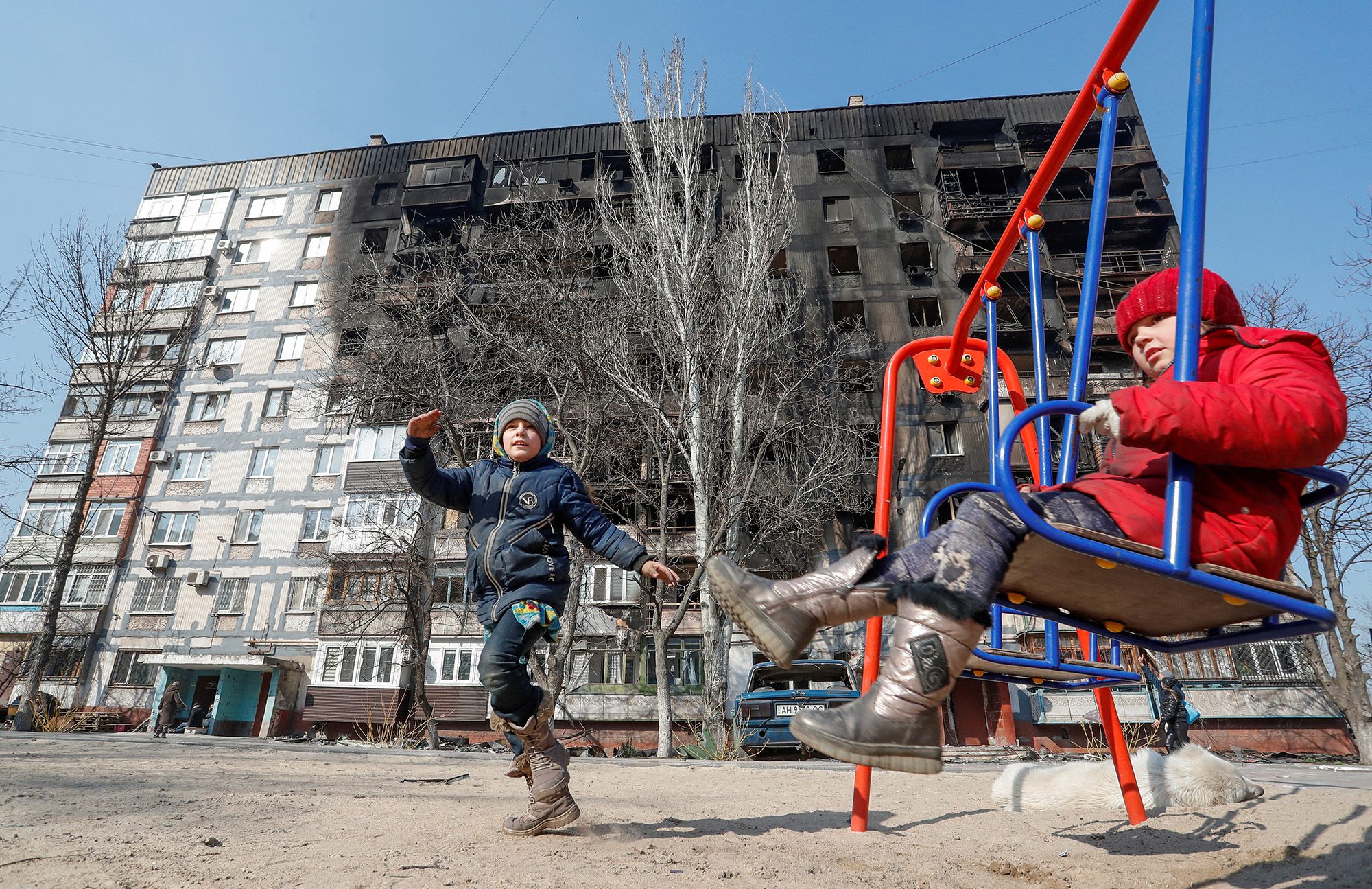 Kinder spielen am 23. März vor einem beschädigten Gebäude im südlichen Hafen von Mariupol, Ukraine.
