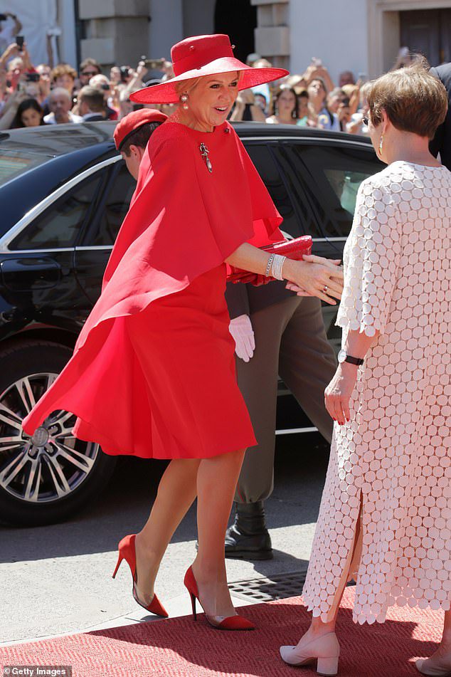 Die dreifache Mutter sorgte in ihrem roten Kleid, das mit einem Cape kommt und perfekt zu ihren Absätzen, ihrem Hut und ihrer Clutch passt, für Aufsehen