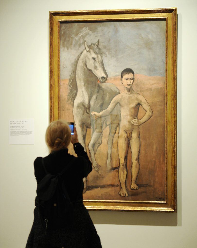 Eine Frau macht ein Handyfoto "Junge, der ein Pferd fährt" 1905-06 von Pablo Picasso.