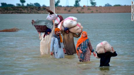 Eine vertriebene Familie watet am 24. August durch ein überschwemmtes Gebiet in Jaffarabad, einem Distrikt der südwestpakistanischen Provinz Belutschistan.