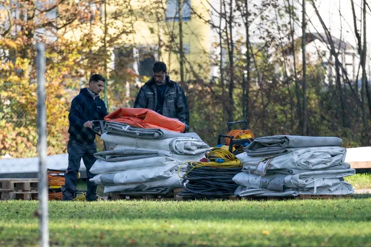 Two men dismantle tents tents that were set up as shelters for refugees in St. Georgen im Attergau, Austria, Monday, Nov. 14, 2022. In a weeks-long standoff with the Austrian government over the accommodation of rising numbers of asylum seekers in the alpine country, the mayor of the small village St. Georgen defied national housing measures and ordered the dismantling of more than a dozen tents for some 100 migrants in his community citing security concerns. (AP Photo/Andreas Schaad)